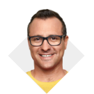 A man wearing prescription glasses and a yellow shirt smiling