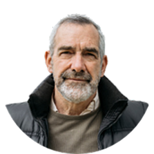 Man with grey hair and beard, wearing a black jacket and smiling